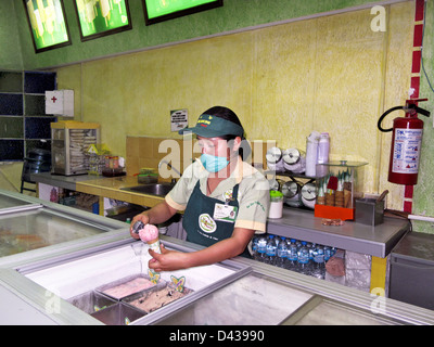 Zähler-Mädchen mit Maske über ihren Mund & Nase Aufbau Erdbeer Kegel an La Michoacana Eisdiele Oaxaca de Juárez, Mexiko Stockfoto