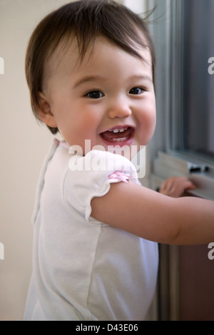 Lächelnden Baby vor einem Fenster Stockfoto