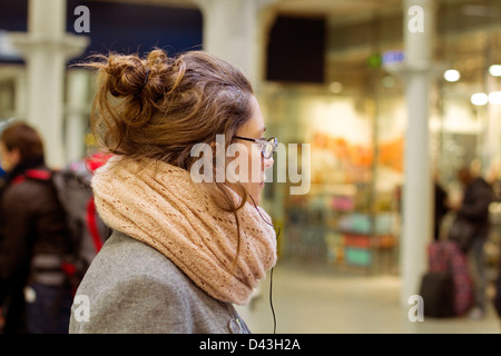 Junge Frau wartet in Kings Cross Station London Stockfoto