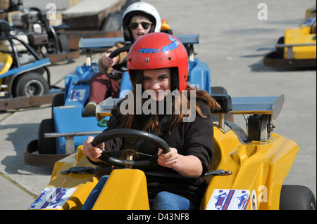 Junges Mädchen Go-Kart-Fahrer in einem roten Helm Rennen vor einem jungen auf eine Go-Kart-Bahn ermittelt Stockfoto