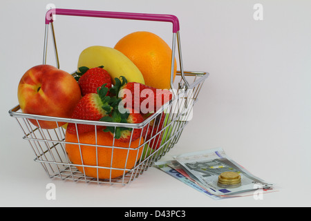 Miniatur Warenkorb gefüllt mit frischem Obst neben Bargeld Stockfoto