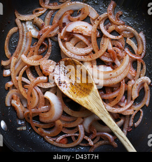 Draufsicht der Pfanne roter Zwiebeln in die Pfanne und Kochlöffel Stockfoto