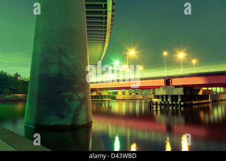 Support für riesige Highway im Vordergrund mit roten Brücke beleuchtet bei Nacht in Tokio, Japan Stockfoto