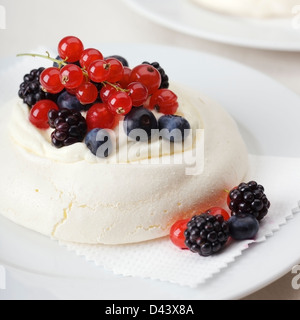 Pavlova mit Sahne, Heidelbeeren, rote Johannisbeeren und Brombeeren. Stockfoto