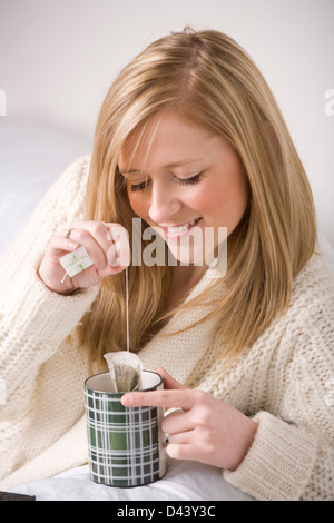 Junge blonde Frau mit einer Tasse Tee auf dem Sofa entspannen. Stockfoto