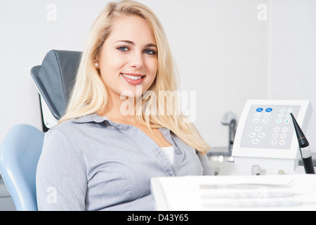 Junge Frau sitzt im Zahnarztstuhl in Zahnarztpraxis für Termin, Deutschland Stockfoto