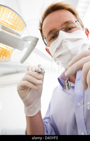 Denitst tragen von Mundschutz und Holding Dentalinstrumente blickte, Deutschland Stockfoto