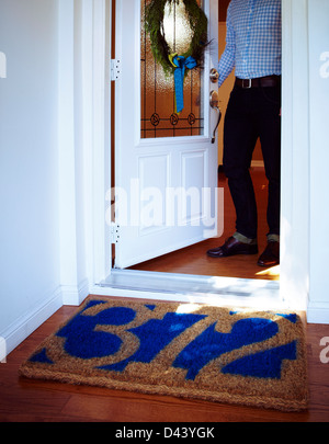 Mann öffnet die Tür zu Hause mit willkommene Matte mit Hausnummer und Kranz an Tür, Toronto, Ontario, Kanada Stockfoto