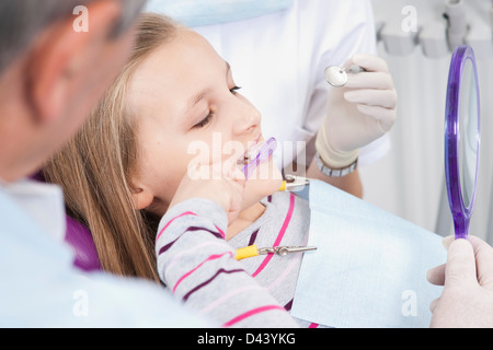 Mädchen Zähneputzen mit Zahnarzt und Hygieniker während Termin, Deutschland Stockfoto