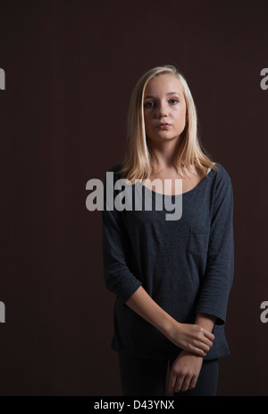 Porträt von Blond, Teenager-Mädchen Blick in die Kamera, Studio Shot auf schwarzem Hintergrund Stockfoto