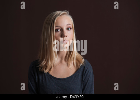 Porträt von Blond, Teenager-Mädchen Blick in die Kamera, Studio Shot auf schwarzem Hintergrund Stockfoto