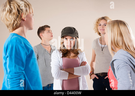 Porträt von Teenager-Mädchen in die Kamera, stehend in der Mitte der Gruppe der Teenager-Jungen und Mädels tragen Baseball Mütze suchen Stockfoto