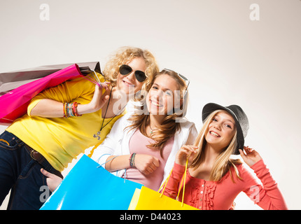 Porträt von drei, coole Mädchen im Teenageralter, Blick in die Kamera Lächeln, gedreht Holding Einkaufstaschen, Studio auf weißem Hintergrund Stockfoto