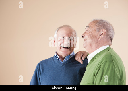 Porträt von zwei älteren Männern gemeinsam lachen, gedreht Studio auf Beige Hintergrund Stockfoto