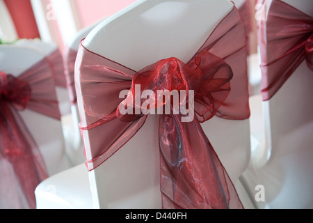 Burgunder chiffon Schleife gebunden um weißen Stoff Stuhl zurück bei Hochzeitsfeiern Stockfoto