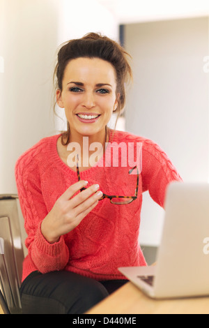 Entspannte Frau am Hause halten ihre Brille beim Sitzen Stockfoto