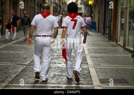 Junge Männer Fuß durch die Straßen von Pamplona Tracht der roten und weißen während San Fermin Festival. Pamplona, Stockfoto