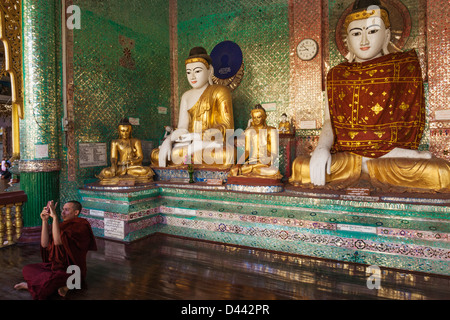 Myanmar, Yangon, Shwedagon-Pagode, Buddha-Statuen und Mönch Stockfoto