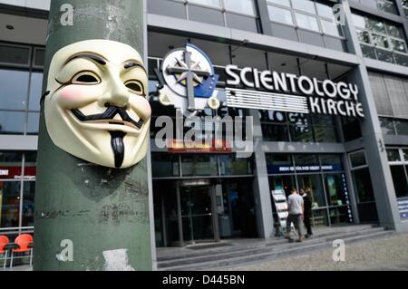 Eine anonyme Maske (auch: Guy Fawkes Maske oder Vendetta Maske) ist auf einem Lichtmast vor der Scientology Kirche in Otto-Suhr-Allee in Berlin, Deutschland, 24. August 2011 abgebildet. Über der Tür befindet sich die Schrift „Scientology Kirche“ und das Scientology Kreuz darunter im Inneren des Gebäudes. Die Schrift „Finde es selbst heraus“ kann gelesen werden. Fotoarchiv für ZeitgeschichteS.Steinach Stockfoto