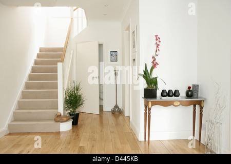 Orchidee im Topf auf kleiner Konsole Tisch im Weißen Saal mit Parkett und Treppe mit beigen Teppich Stockfoto
