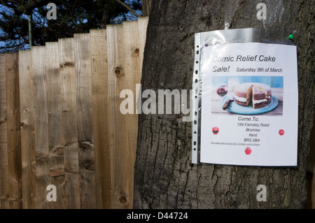 Ein Schild an einem Baum gepinnt wirbt einen Verkauf von Kuchen zugunsten von Comic Relief Stockfoto
