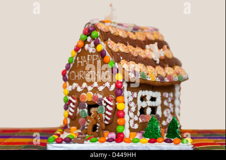 Horizontale Nahaufnahme ein Lebkuchenhaus zu Weihnachten mit Schnee und Weihnachtsbäume dekoriert. Stockfoto