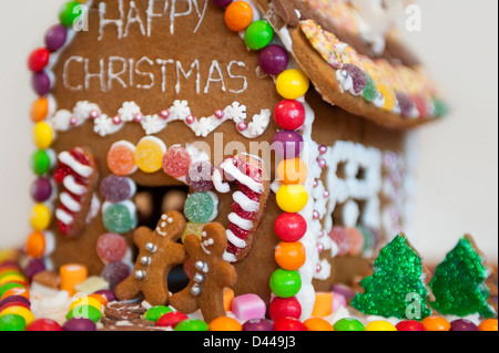 Horizontale Nahaufnahme ein Lebkuchenhaus zu Weihnachten mit Schnee und Weihnachtsbäume dekoriert. Stockfoto