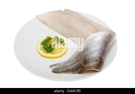 Rohe Pollock Fischfilet auf einem Teller mit Zitrone und Petersilie isoliert gegen weiß Stockfoto