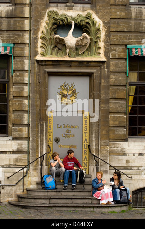 Junge Menschen ruht auf Stufen des La Maison De Cygne Restaurant am Grand Place in Brüssel Stockfoto