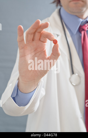 Männlichen Arzt hält eine Pille Nahaufnahme Bild mit geringer Tiefe von eingereicht mit Fokus auf Seite mit einer Kur. Stockfoto