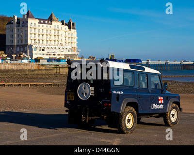 RNLI-Rettungsboot unterstützen Landrover geparkt am North Shore Strand Llandudno North Wales UK mit dem Grand Hotel im Hintergrund Stockfoto