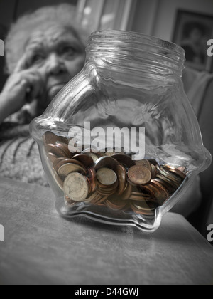 INFLATION SENIOREN GELD SPAREN POT besorgt ältere ältere ältere ältere Dame in ihrem Wohnzimmer mit Geld sparen Pot auf Tisch B&W/Colour Stockfoto