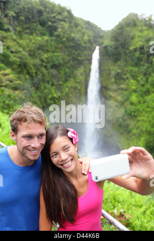 Glückliche junge multiethnischen paar Selbstportrait-Aufnahme mit Kamera-Handy auf Hawaii, große Inseln, Akaka Wasserfälle Stockfoto