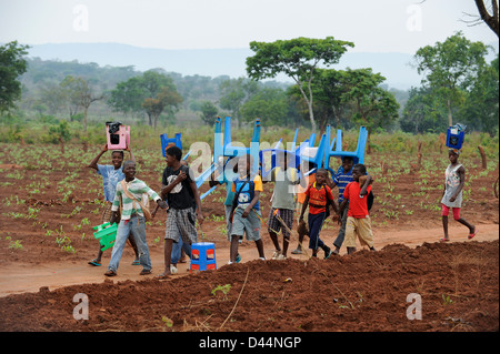 ANGOLA Kwanza Sul, Dorf Kassombo, Kinder zur Schule tragen ihre Plastikstühle von zu Hause aus Stockfoto