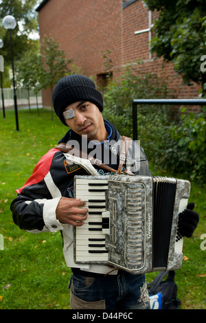 Ein Roma-junge mit einem beschädigten Auge spielt Akkordeon und betteln. Stockfoto