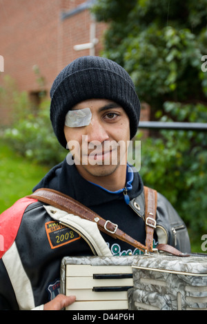 Ein Roma-junge mit einem beschädigten Auge spielt Akkordeon und betteln. Stockfoto