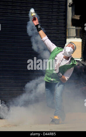 5. März 2013 - A Kashmiri Demonstranten werfen wieder eine Träne Rauch Shell auf indische Polizisten bei einem Zusammenstoß zwischen Demonstranten und indische Polizei in Srinagar, der Sommerhauptstadt des indischen Kaschmir auf 03.05.2013, normales Leben wurde für den zweiten Tag in Folge heute durch einen Marsch durch eine Gruppe von Separatisten, die Residenz des kaschmirischen Student namens getroffen , wer fand man in seinem Hostel Zimmer in Hyderabad hängen. Behörden haben Polizei und paramilitärische Personal in großer Zahl in der südlichen Kaschmir Pulwama Stadt, die Geburtsregion des Mudasir Kamran, (25), die gefunden wurde, an der Decke von seinem h bereitgestellt Stockfoto