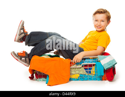 lustiger Blondschopf sitzen in Haufen Kleider Stockfoto