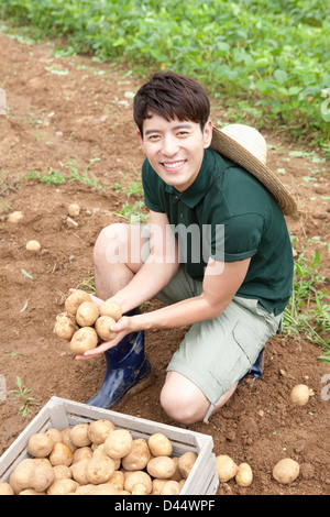 ein Mann mit Bauernmarkt Hut mit Kartoffeln in einer farm Stockfoto