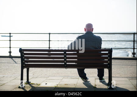 Southend, Essex, England. 5. März 2013. Menschen genießen die ungewöhnlich warmen Tag. Allein Reifen männlichen, sitzen auf einer Bank im alten Leigh, Blick auf die Themse-Mündung, Kent in der Sonne.  Bildnachweis: Allsorts Stock Foto / Alamy Live News Stockfoto