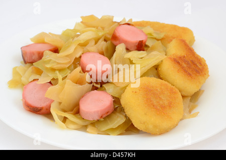 Gedünstetem Kohl mit gegrillten Würstchen und Nuggets auf einem Teller Stockfoto