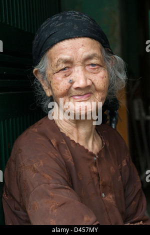 Alte Frau mit einem gefütterten Facesitting in einer Gasse in die alten Viertel von Hanoi, Vietnam