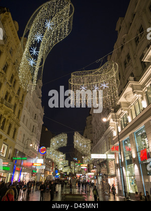 Abendspaziergang auf Karntnerstrasse. Kärntner Straße, eine High-End-Einkaufsstraße in Wien mit Käufern und Weihnachtsbeleuchtung Stockfoto