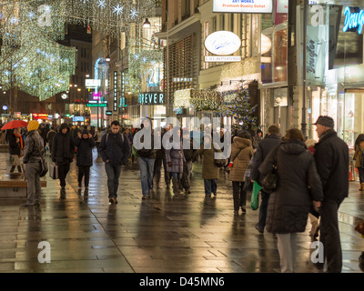 Abendspaziergang auf Karntnerstrasse. Kärntner Straße, eine High-End-Einkaufsstraße in Wien mit Käufern und Weihnachtsbeleuchtung Stockfoto