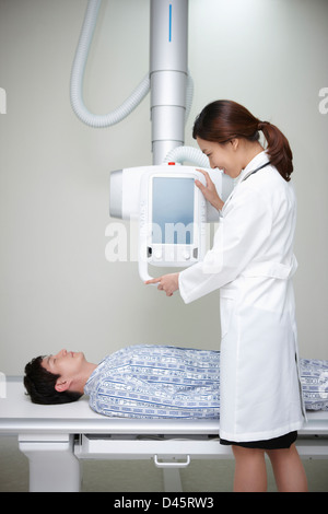 ein Patient liegt auf dem Bett und ein Arzt mit X-Ray Maschine Stockfoto