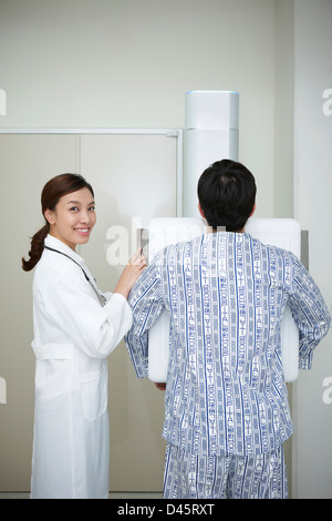 ein Arzt, ein Patient, seine Brust auf X-Ray Maschine neben Stockfoto
