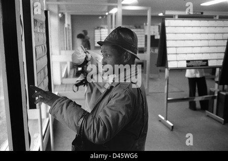 Arbeitslosenarbeitsplatz Arbeitsbörse. Ein schwarzer britischer Mann in einem Job Centre des Department of Health and Social Security (DHSS) - Labour Exchange scannt die Notiztafeln nach freien Stellen in South London. Er ist auf der Flucht und sucht Arbeit. Multiethnisches Großbritannien im 1970er 1976. Vereinigten Königreich. HOMER SYKES Stockfoto