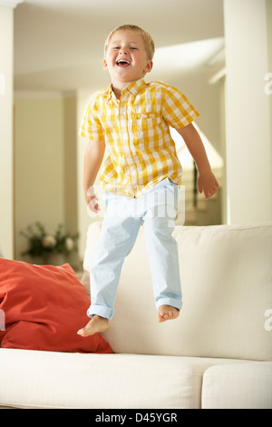 Junge springt auf Sofa zu Hause Stockfoto