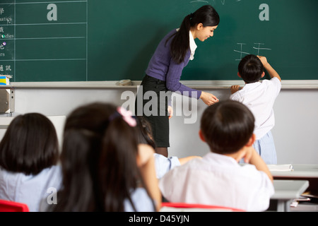 Männliche Schüler schreiben auf Tafel In Chinesisch Schule Unterricht Stockfoto