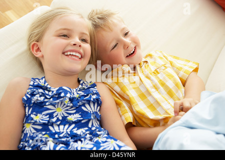 Zwei Kinder lag kopfüber auf Sofa zu Hause Stockfoto